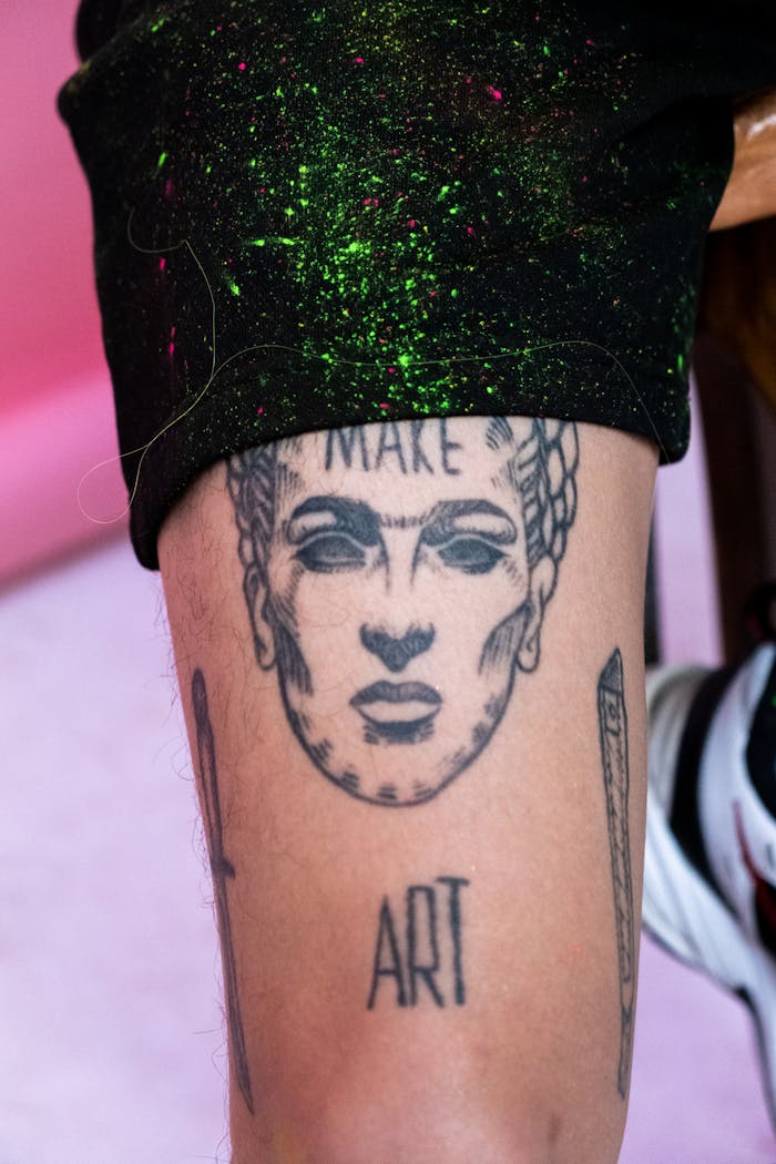 Close-up of a Frida Kahlo inspired tattoo on a leg featuring artistic elements.